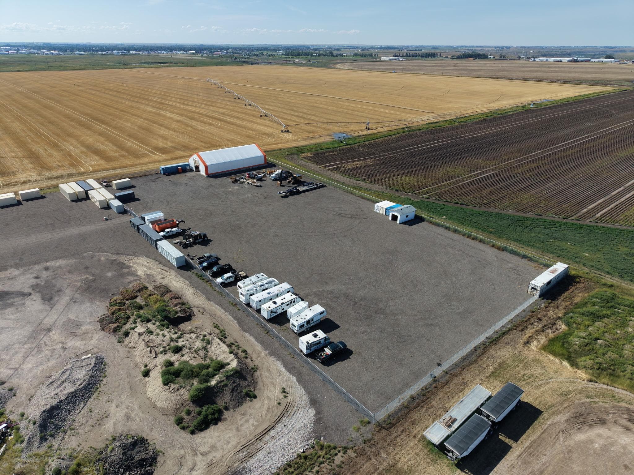 Aerial view of the open gravel RV storage lot surrounded by prairie fields in Taber